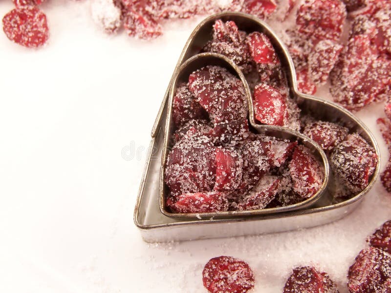 Image of dried cranberries mixed with white granulated sugar, placed within two different sized heart-shaped metal cookie cutters. Image of dried cranberries mixed with white granulated sugar, placed within two different sized heart-shaped metal cookie cutters.