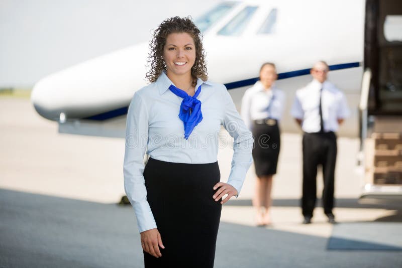 Airhostess With Hand On Hip Standing At Airport stock photos