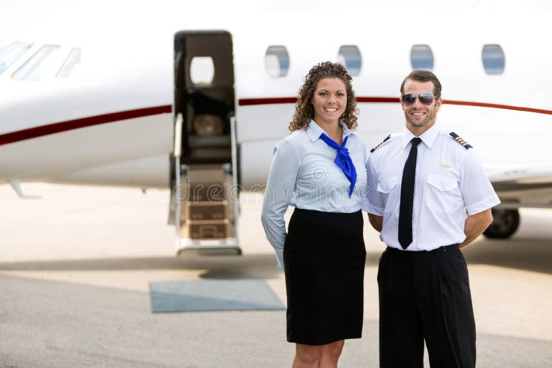 Airhostess And Pilot Standing Against Private Jet royalty free stock photos