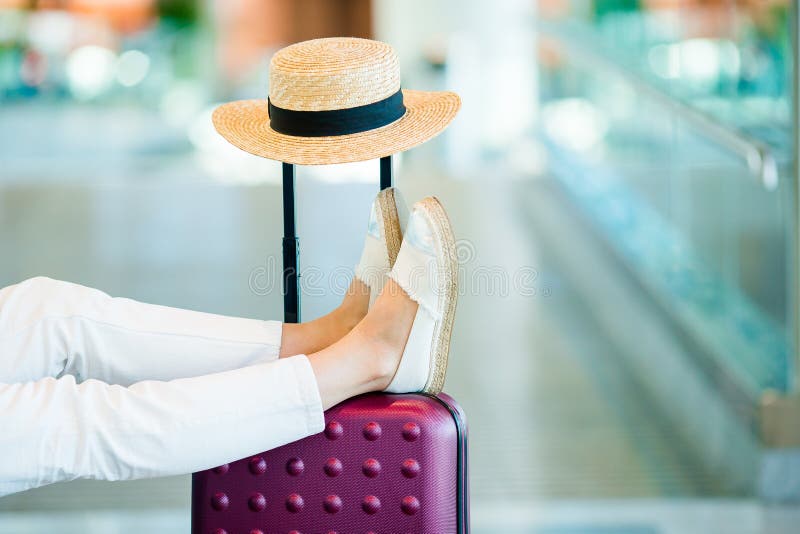 Young woman in an airport lounge waiting for landing. Closeup legs on the baggage