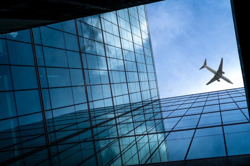 Airplane flying above modern glass office building. Perspective view of futuristic glass building. Exterior of office glass stock photography
