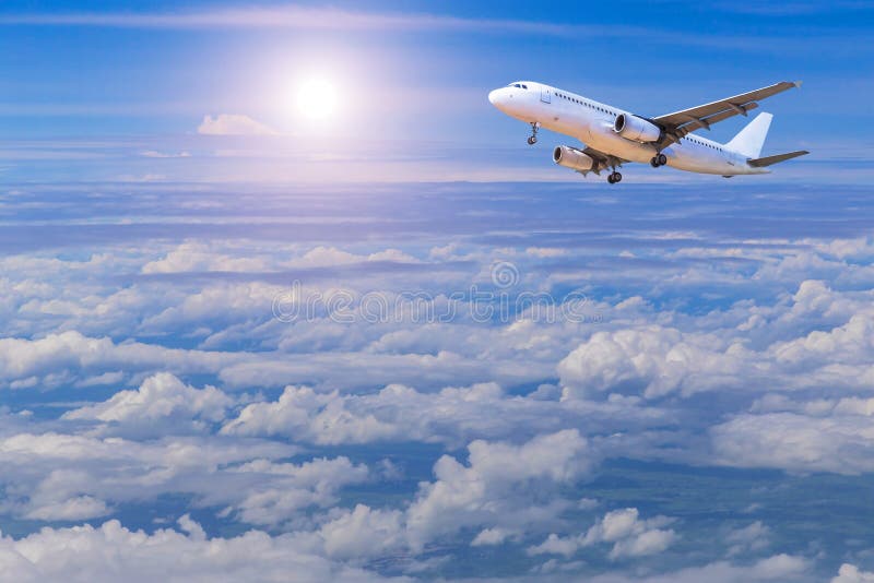 Airplane flying away in to sky high altitude above the white clouds with sunlight.