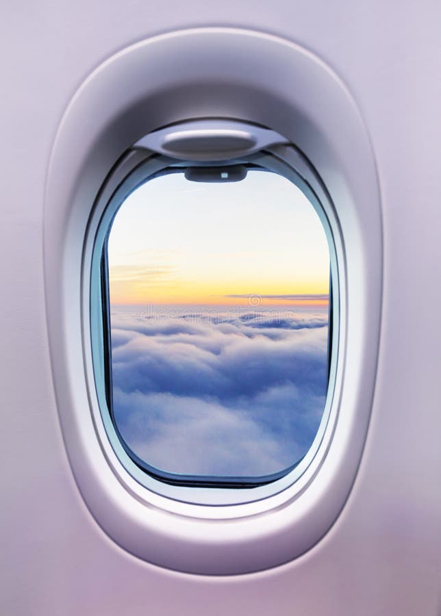 Airplane interior with window view of sunset above clouds