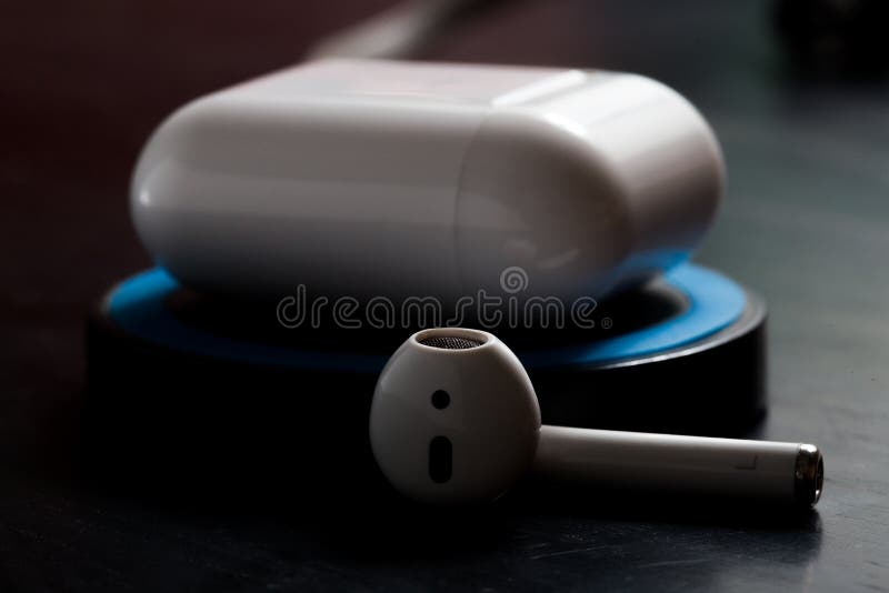 Airpod with charging case on  wireless charger in low key lighting