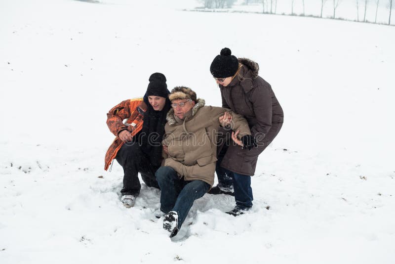 Aiuto senior di incidente e della gente della neve fotografia stock Aiuto senior di incidente e della gente della neve fotografia stock