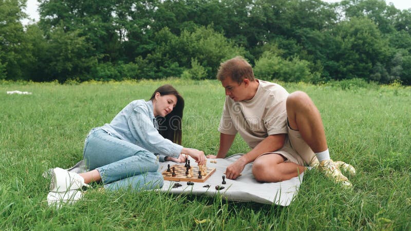 Ajedrez. un alegre partido de ajedrez de verano en la naturaleza una pareja joven que disfruta de su tiempo libre. juego de mesa d almacen de video