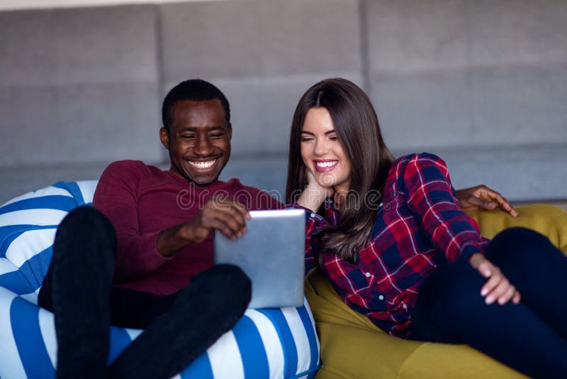 Ajouter heureux au comprim? et au smartphone d'ordinateur sur un sofa photo libre de droits Ajouter heureux au comprim? et au smartphone d'ordinateur sur un sofa photo libre de droits
