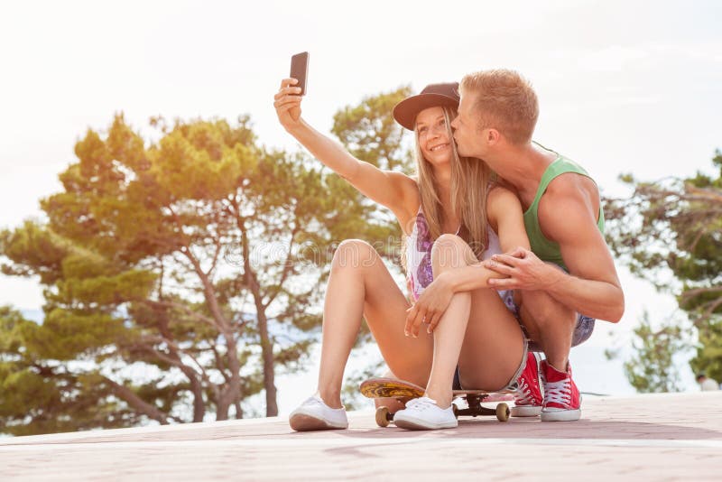 Ajouter heureux à se reposer sur la planche à roulettes et à prendre un selfie photo stock