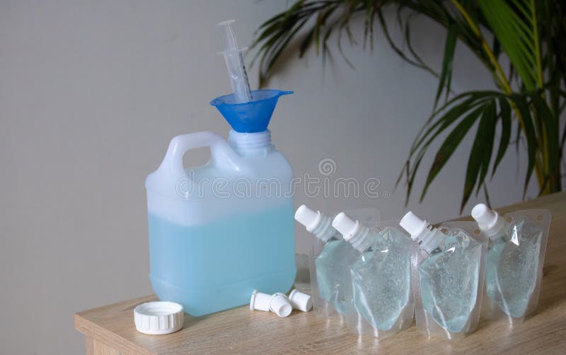 Ajoutez Le Gel D'alcool Du Seau De Gallon Au Sac De Sac De Gel D'alcool.  Sur La Table Et Le Mur Blanc. Pour Les Anti Se Laver Les Photo stock - Image