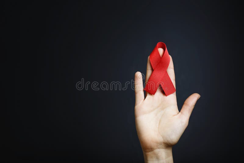 Aids ribbon on hands, hiv, red ribbon symbol of struggle, on dark background. Aids ribbon on hands, hiv, red ribbon symbol of struggle, on dark background