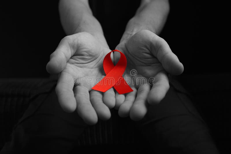 Aids ribbon on hands black & white, hiv, on dark background, red ribbon symbol of struggle. Aids ribbon on hands black & white, hiv, on dark background, red ribbon symbol of struggle