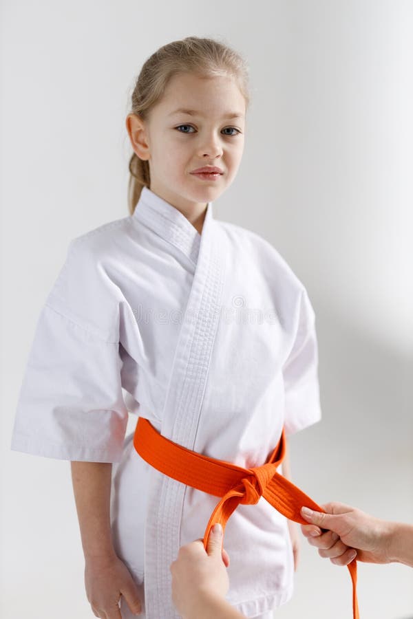 Help tie an orange belt to a child for karate lessons. Help tie an orange belt to a child for karate lessons.