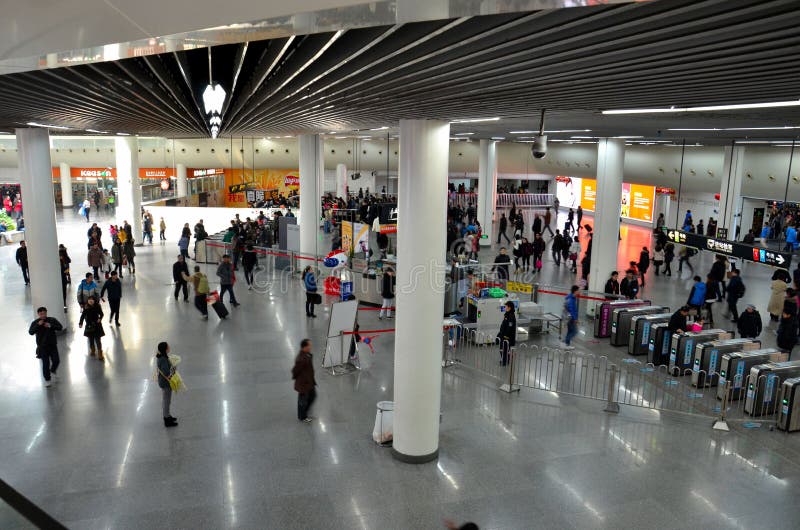 Shanghai, China - February 15, 2013: The concourse at the People's Square metro station in Shanghai, China. The People's Square is located in a central area of Shanghai, reflected in the size of the station which includes shops and other commercial establishments. Subway travelers can be seen moving about the station as well as proceeding through ticket turnstiles and security x-ray machines. Shanghai, China - February 15, 2013: The concourse at the People's Square metro station in Shanghai, China. The People's Square is located in a central area of Shanghai, reflected in the size of the station which includes shops and other commercial establishments. Subway travelers can be seen moving about the station as well as proceeding through ticket turnstiles and security x-ray machines.