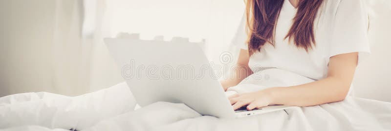 Ajuste asiático bonito da jovem mulher do Web site da bandeira na utilização da cama fotos de stock royalty free Ajuste asiático bonito da jovem mulher do Web site da bandeira na utilização da cama fotos de stock royalty free