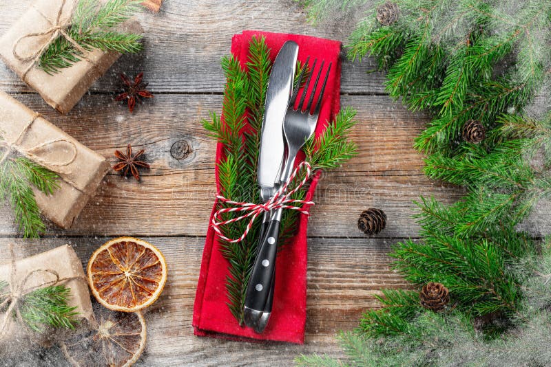 Ajuste de la tabla de la Navidad con las placas, los cubiertos, la caja de regalo y las decoraciones en un fondo de madera oscuro foto de archivo Ajuste de la tabla de la Navidad con las placas, los cubiertos, la caja de regalo y las decoraciones en un fondo de madera oscuro foto de archivo