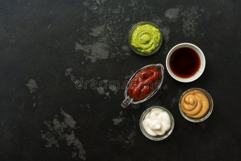 Set of various sauces in bowls on a black stone background. Mustard sauce, tomato, wasabi, mayonnaise, soy. Top view, copy space. Set of various sauces in bowls on a black stone background. Mustard sauce, tomato, wasabi, mayonnaise, soy. Top view, copy space.