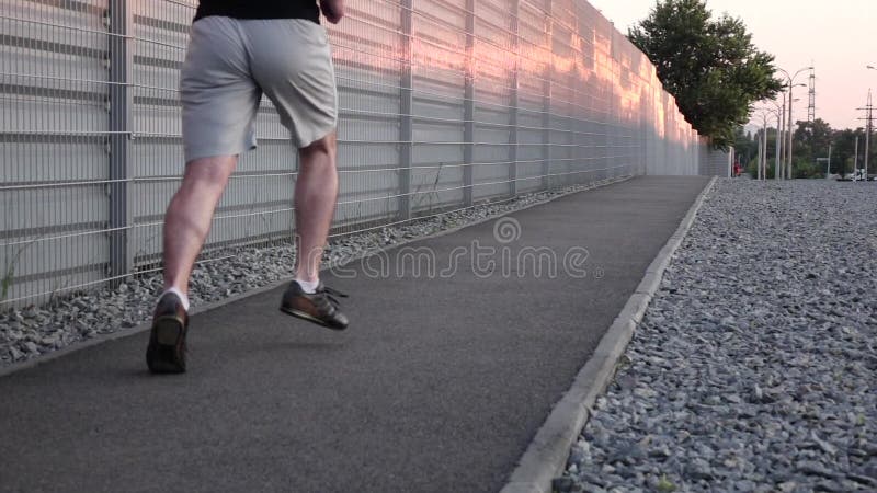Ajuste e homem novo saudável que correm através da rua Movimento lento