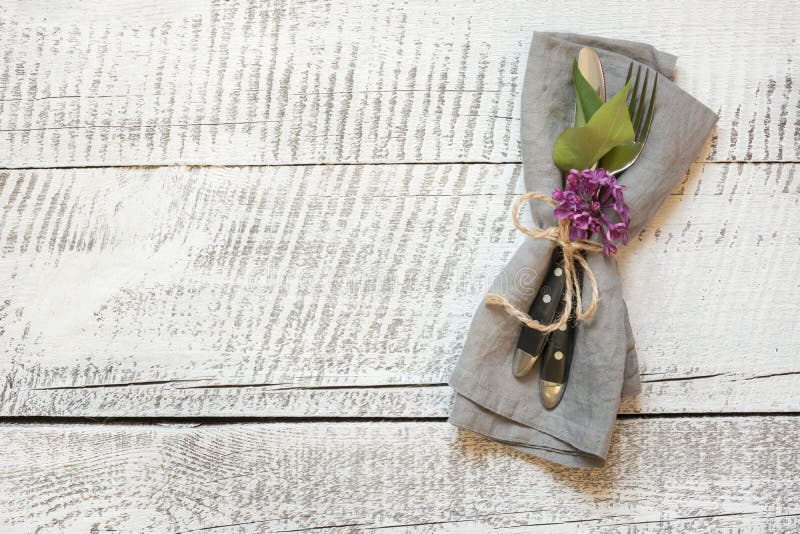 Ajuste festivo da tabela da mola com cutelaria e a flor lilás na tabela de madeira branca Copie o espa?o Configura??o lisa fotografia de stock royalty free Ajuste festivo da tabela da mola com cutelaria e a flor lilás na tabela de madeira branca Copie o espa?o Configura??o lisa fotografia de stock royalty free