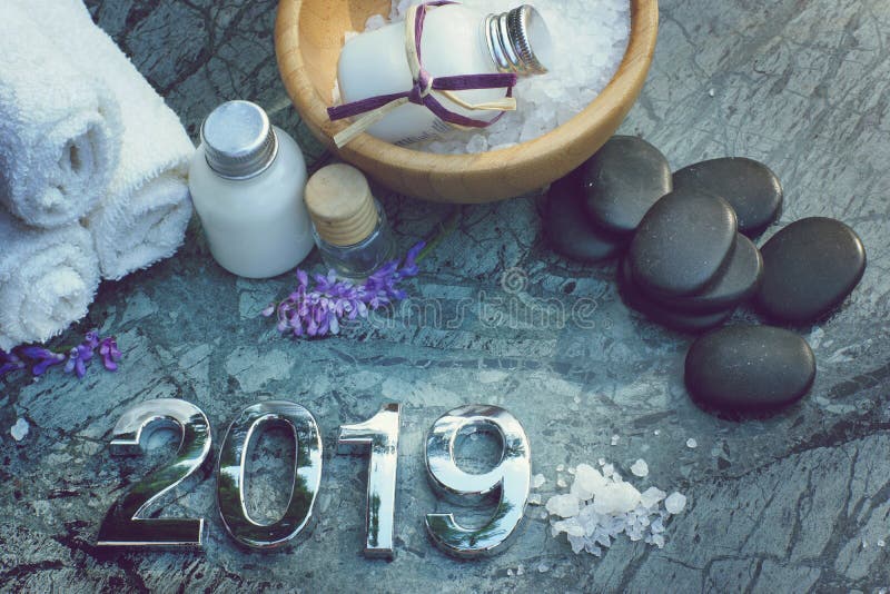 Ajuste para tratamentos dos termas em 2019 na pedra de mármore com figuras, sal de banho e toalhas e pedras pretas para a massage foto de stock Ajuste para tratamentos dos termas em 2019 na pedra de mármore com figuras, sal de banho e toalhas e pedras pretas para a massage foto de stock
