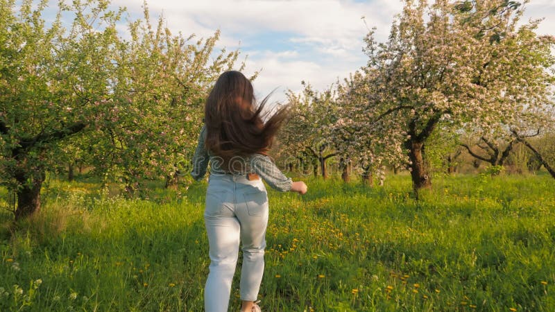 Aktiv tonåring-flicka som springer genom att blomma äppelfrukten