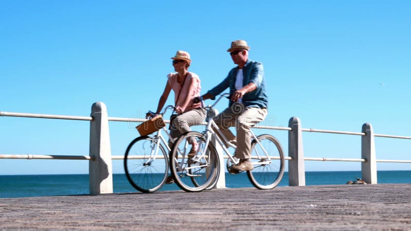 Aktiva pensionärer som går på en cykel, rider vid havet