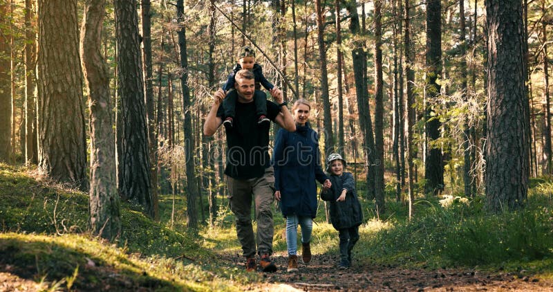 Aktive junge Familienwanderungen auf dem Waldweg mit Kindern. Sohn, der auf Papa sitzt