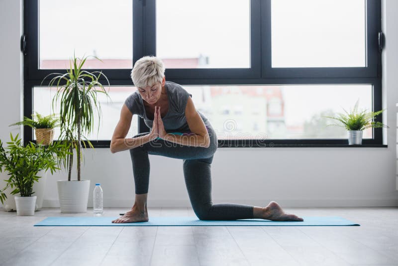 Aktive Ã¤ltere Frau, die in InnenrÃ¤umen Yoga praktiziert
