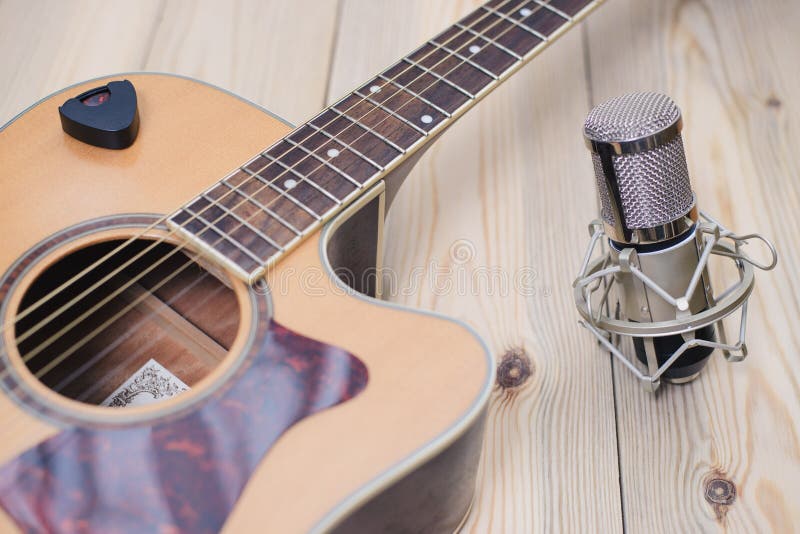 Akustikgitarre, die gegen einen hölzernen Hintergrund stillsteht lizenzfreies stockbild Akustikgitarre, die gegen einen hölzernen Hintergrund stillsteht lizenzfreies stockbild