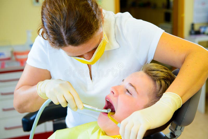 Al dentista de sexo femenino trata al muchacho foto de archivo libre de regalías Al dentista de sexo femenino trata al muchacho foto de archivo libre de regalías