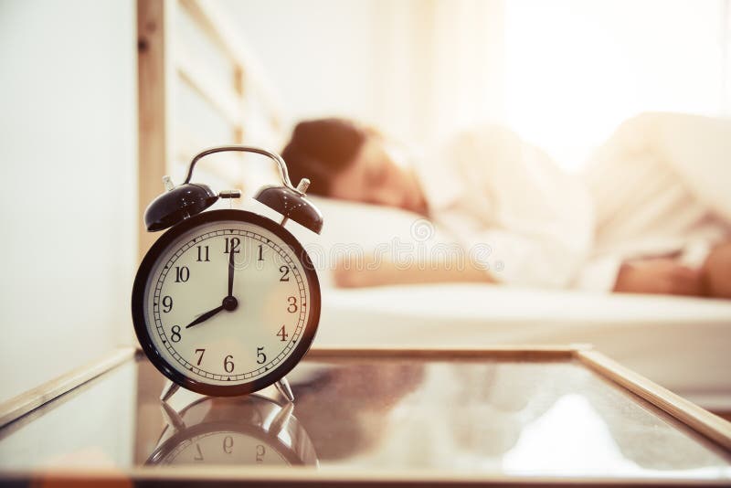 Alarm clock with beauty woman in background. Morning and Lazy time concept. Bedroom theme stock photo