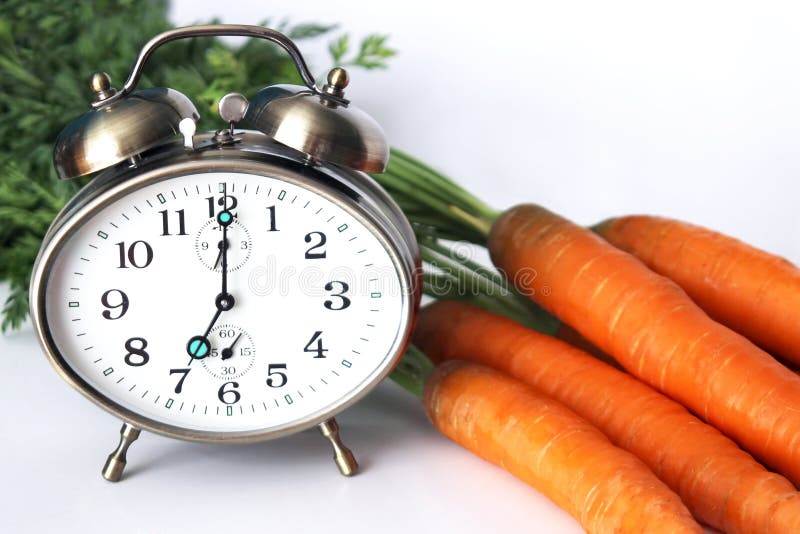 Alarm clock at bunch of fresh carrots on white background. Weight watchers stock images, royalty-free photos and pictures
