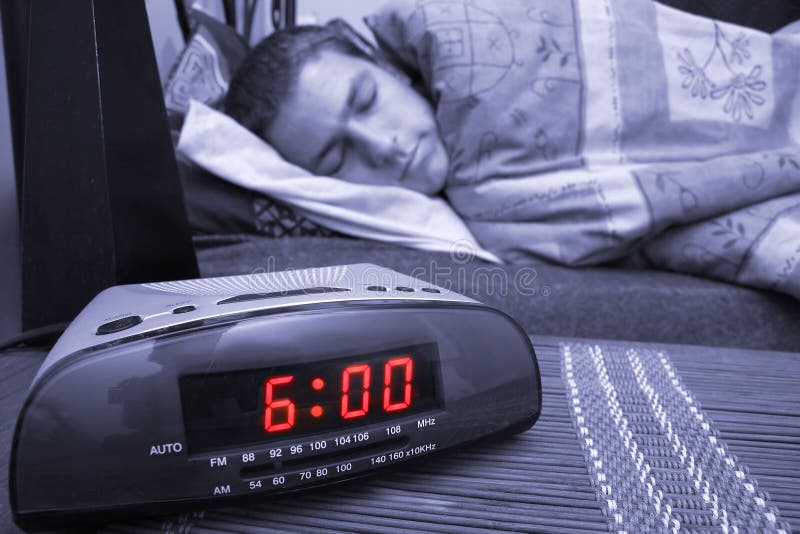 Alarm clock with male model in bed in background. Shallow depth of field. Alarm clock with male model in bed in background. Shallow depth of field