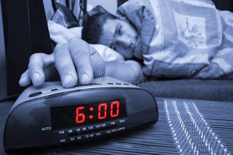 Alarm clock with male model in bed in background. Shallow depth of field. Alarm clock with male model in bed in background. Shallow depth of field