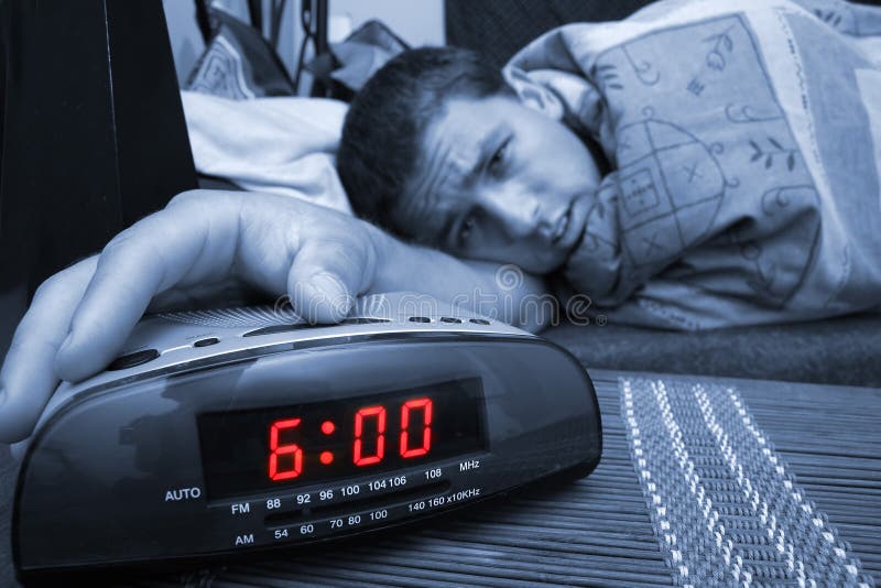 Alarm clock with male model in bed in background. Shallow depth of field. Alarm clock with male model in bed in background. Shallow depth of field