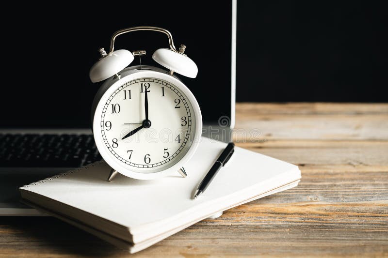 Alarm Clock, Notepad and Laptop at the Workplace, Closeup. Stock