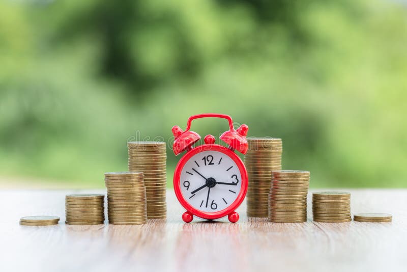 Alarm clock and step of coins stacks on working table. banking and business idea. time for savings money concept stock image
