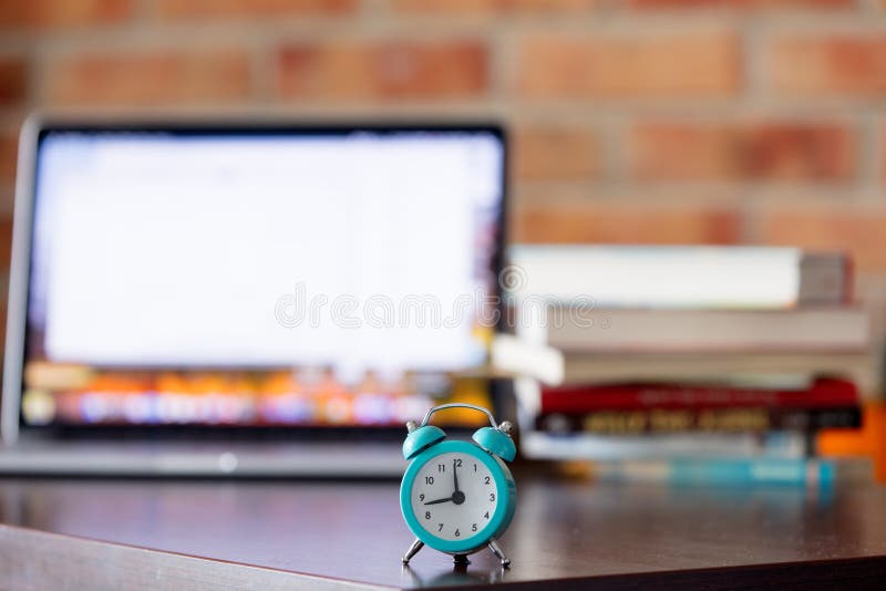 Alarm Clock on a Table with Laptop Computer and Books Stock Photo