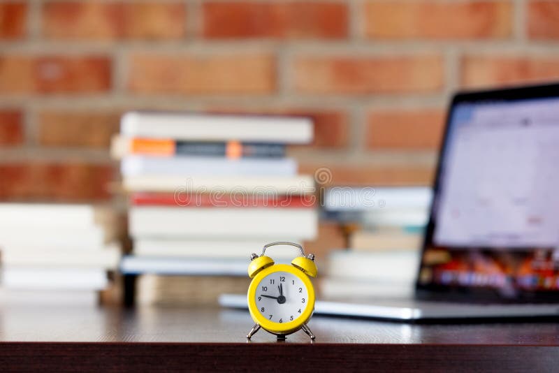 Alarm Clock on a Table with Laptop Computer and Books Stock Image