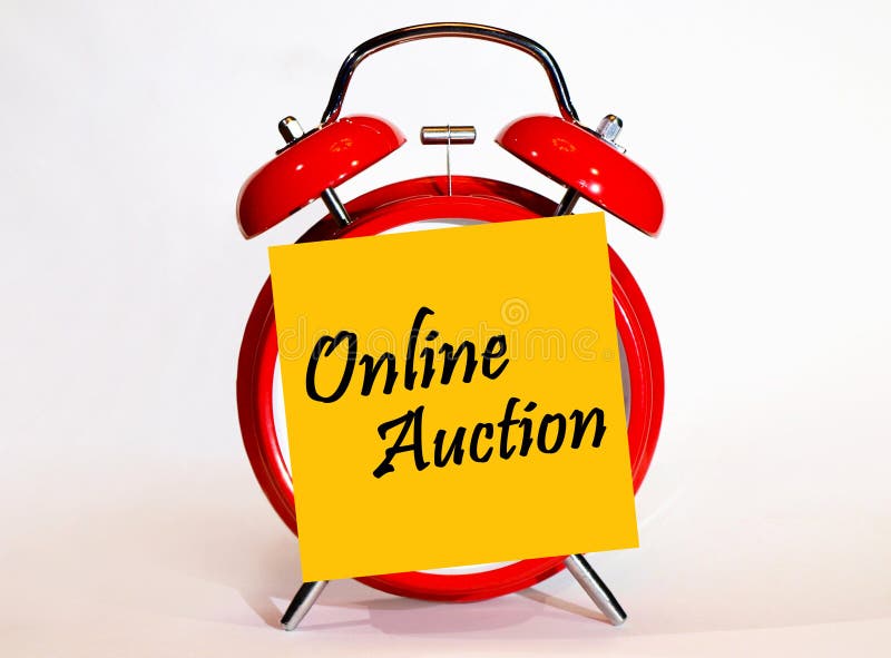 An alarm clock and a yellow note with text online auction.