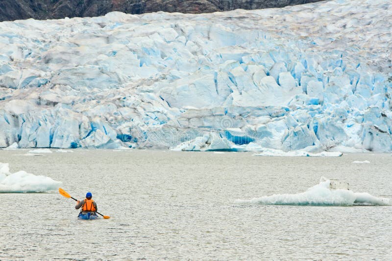 Alaska Kayak Paddling Mendenhall Glacier Lake. A lone kayaker paddling Mendenhall Lake towards the face of Mendenhall Glacier outside Juneau in southeast Alaska stock image Alaska Kayak Paddling Mendenhall Glacier Lake. A lone kayaker paddling Mendenhall Lake towards the face of Mendenhall Glacier outside Juneau in southeast Alaska stock image
