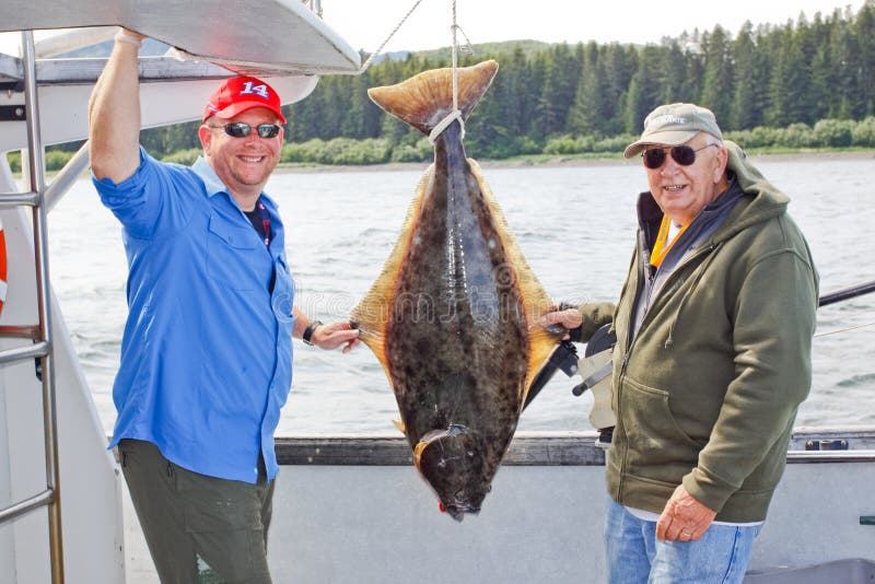 A photo of a smiling family happy father and son with a fresh pacific halibut caught while fishing the waters of Icy Straight near Hoonah, Alaska. A photo of a smiling family happy father and son with a fresh pacific halibut caught while fishing the waters of Icy Straight near Hoonah, Alaska.