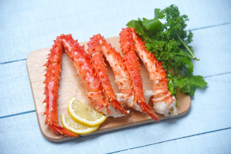 Alaskan King Crab Legs Cooked on wooden cutting board with lemon parsley - red crab hokkaido seafood served table