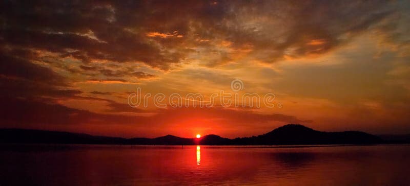Alba cremisi nuvolosa viva con le riflessioni dell'acqua immagine stock libera da diritti Alba cremisi nuvolosa viva con le riflessioni dell'acqua immagine stock libera da diritti