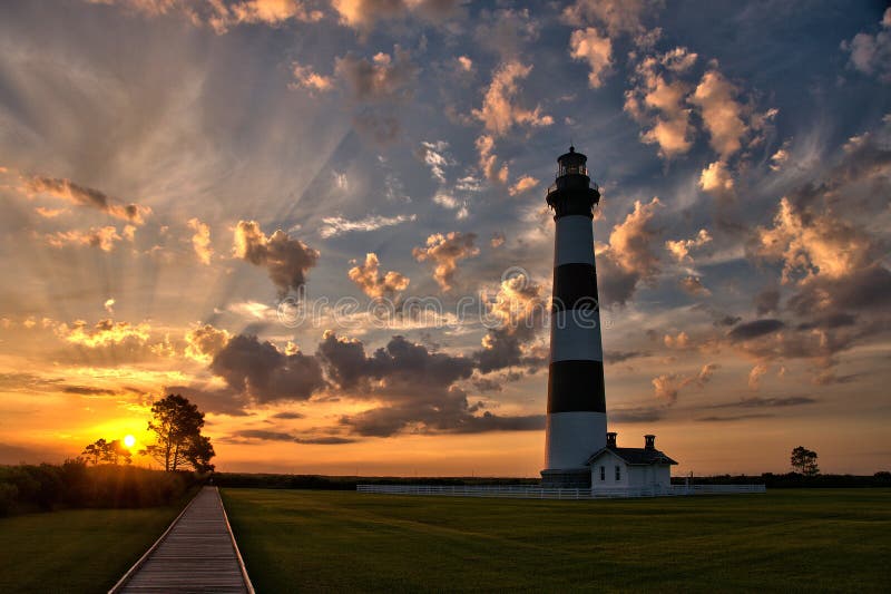 Panoramic shot of early morning light rays streaming through the clouds at sunrise at the Bodie Island Lighthouse in the Outer Banks of North Carolina. Panoramic shot of early morning light rays streaming through the clouds at sunrise at the Bodie Island Lighthouse in the Outer Banks of North Carolina