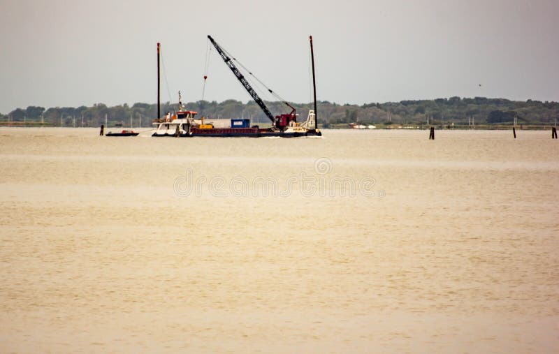Alba, lagoon of venice, panorama that you find yourself entering venice by land. first light, ship performing maintenance on the V stock photo