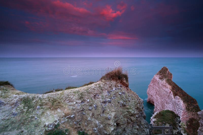 Alba rossa drammatica sopra le scogliere in oceano immagine stock Alba rossa drammatica sopra le scogliere in oceano immagine stock
