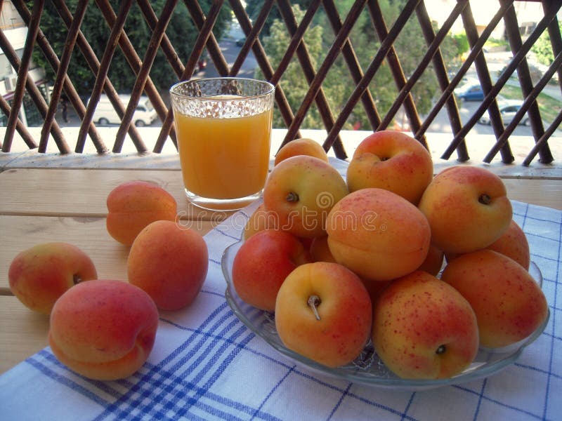 Albaricoques maduros y dulces en una servilleta de la cocina y un vidrio de jugo imagen de archivo libre de regalías Albaricoques maduros y dulces en una servilleta de la cocina y un vidrio de jugo imagen de archivo libre de regalías