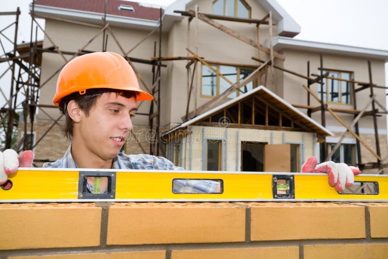 The young builder checks a level of a brick wall. The young builder checks a level of a brick wall.