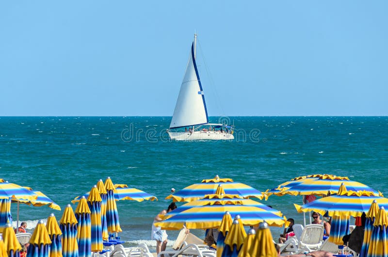ALBENA, BULGARIA - 17 GIUGNO 2017: Avvolga l'yacht della barca sull'acqua blu di Mar Nero vicino alla spiaggia con i turisti immagine stock ALBENA, BULGARIA - 17 GIUGNO 2017: Avvolga l'yacht della barca sull'acqua blu di Mar Nero vicino alla spiaggia con i turisti immagine stock