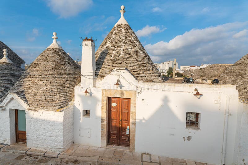 Alberobello - the land of trulli houses on the UNESCO list. Picturesque white houses with stone roofs against the blue sky. Cottages a tourist attraction in royalty free stock photo Alberobello - the land of trulli houses on the UNESCO list. Picturesque white houses with stone roofs against the blue sky. Cottages a tourist attraction in royalty free stock photo